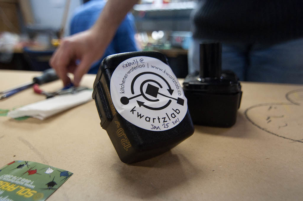 A power-tool battery pack on a workbench, with “12.0V” moulded into the side of the case