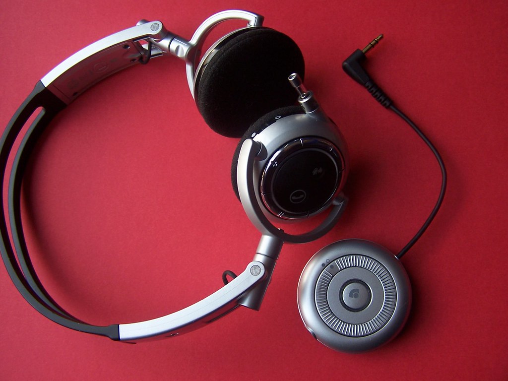 Over-ear headphones next to a round Bluetooth receiver whose cable ends in a 3.5 mm plug